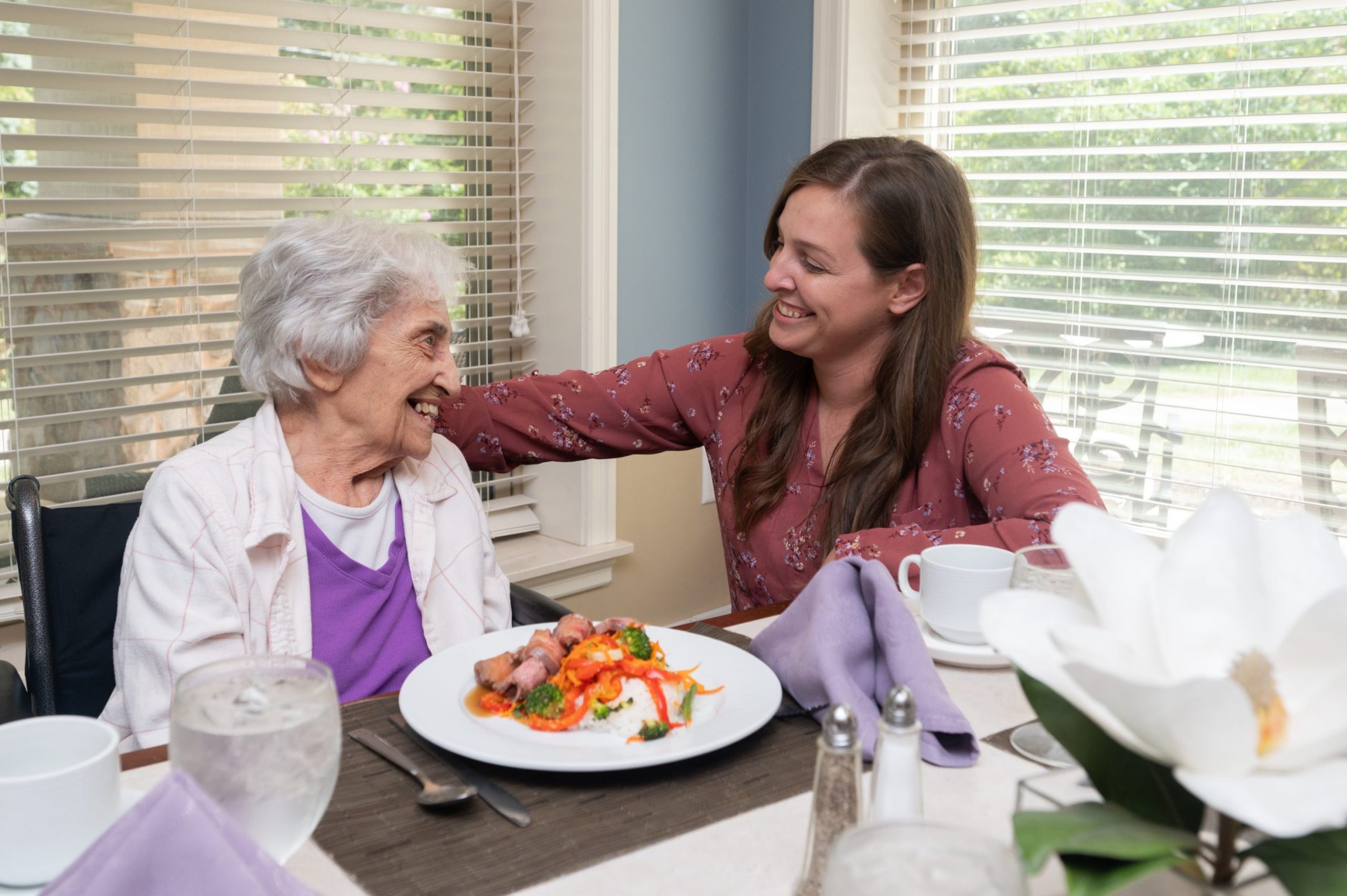 An employee sits with a resident during a meal.