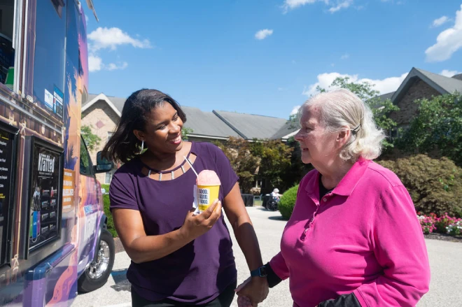 Artman team member hands water ice to Artman resident