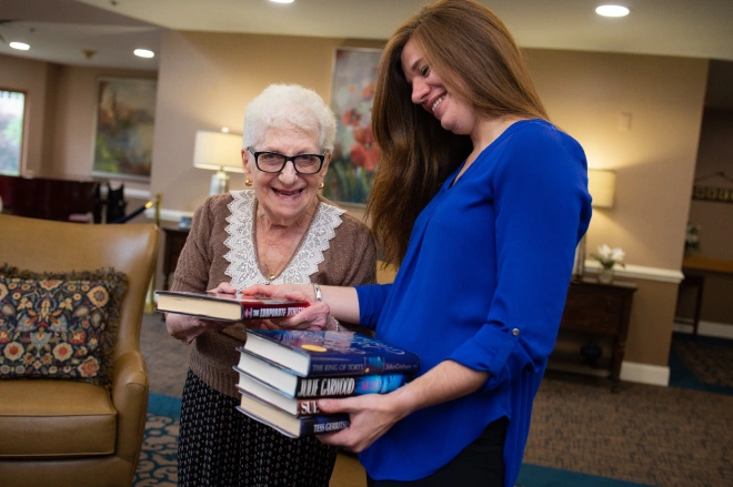 Young Artman team member looks at a stack of books with resident