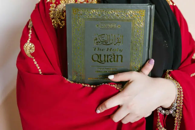 Woman in black hijab holding the Holy Qur'an